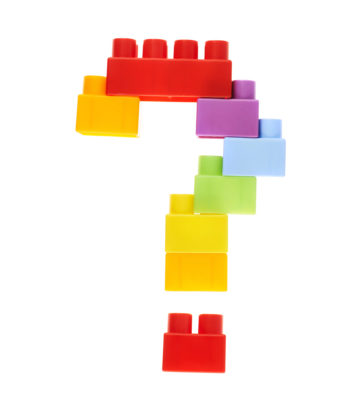 Question mark made of colorful plastic toy construction bricks, isolated over the white background